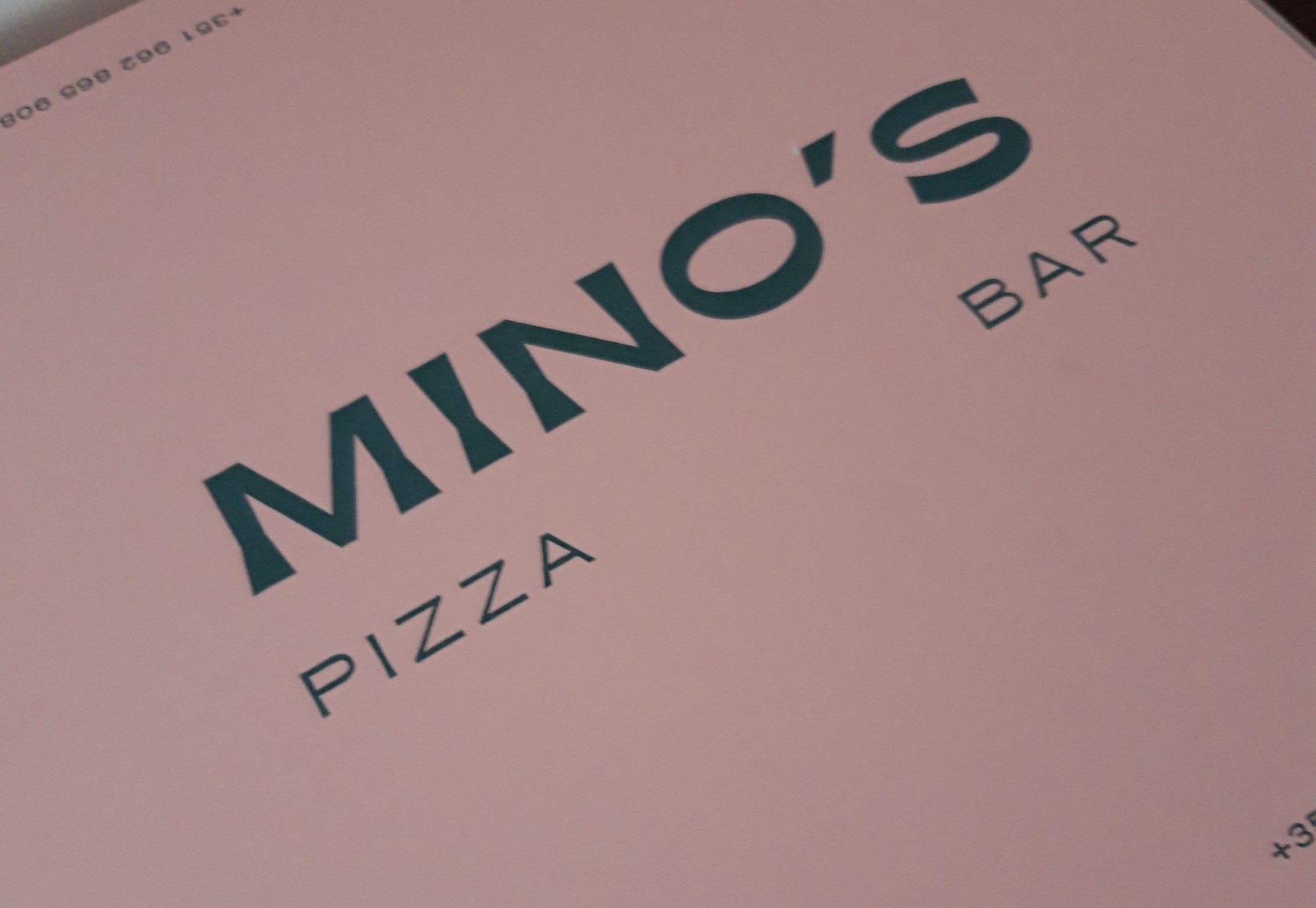 pink pizza box which reads Mino's Pizzeria in turquoise letters